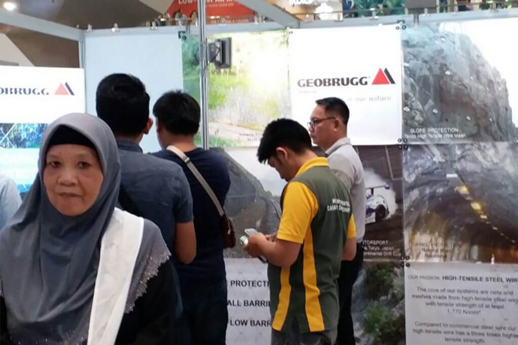 Attendees at a Geobrugg trade show, including a woman in a hijab.