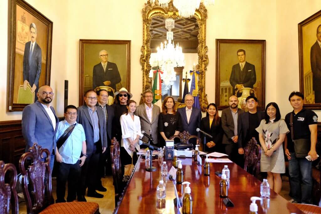 Group photo in a formal room with portraits and a large mirror in Mexico.