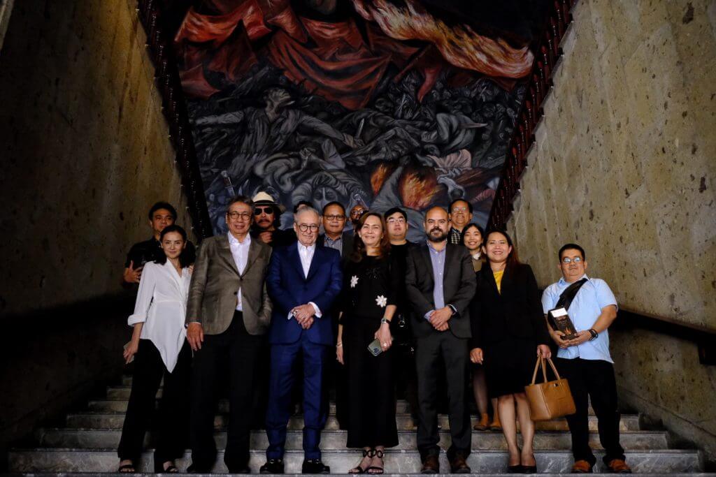 A group of people poses on a staircase in front of a large mural.
