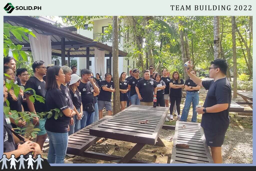 Solid.PH team building event in 2022, with a group gathered outdoors listening to a speaker.