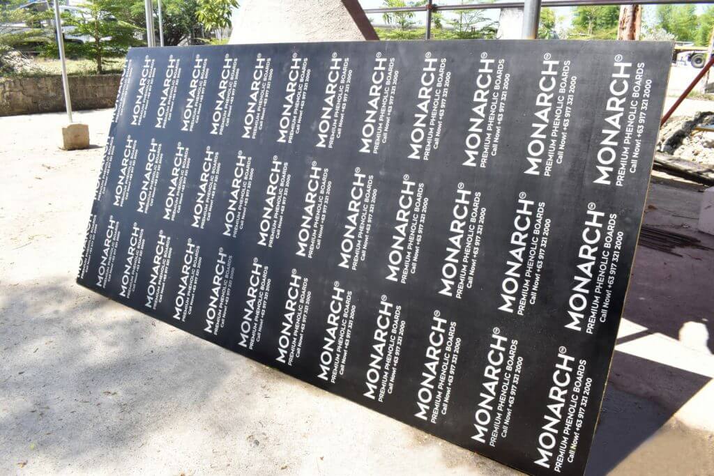 A large sheet of Monarch premium phenolic boards lies on the ground outdoors.